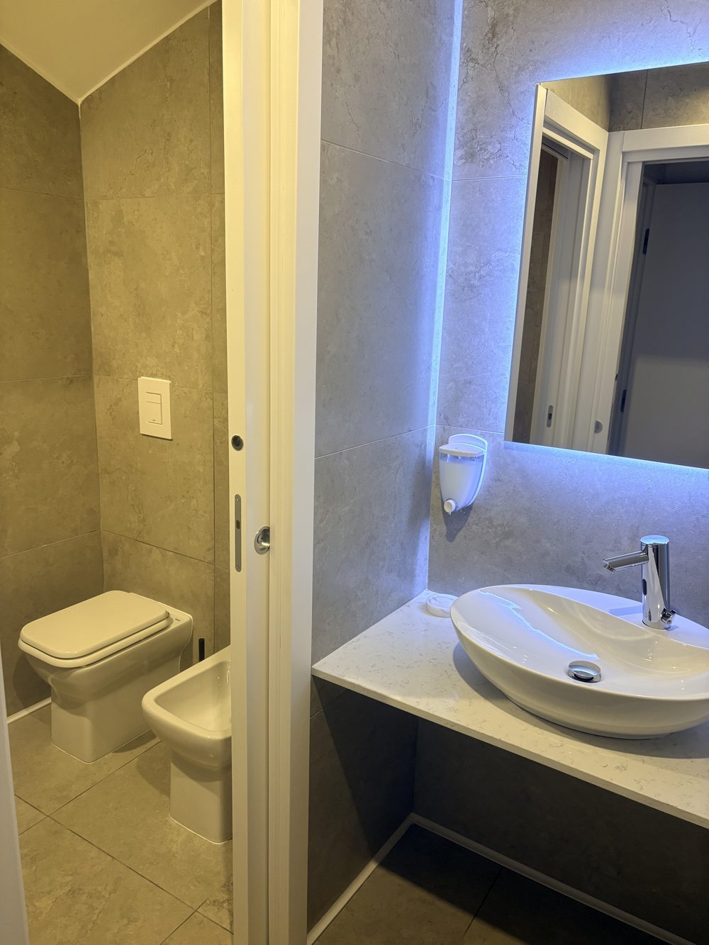 Interno della toilette donne, rifinita in marmo grigio con specchio retroilluminato