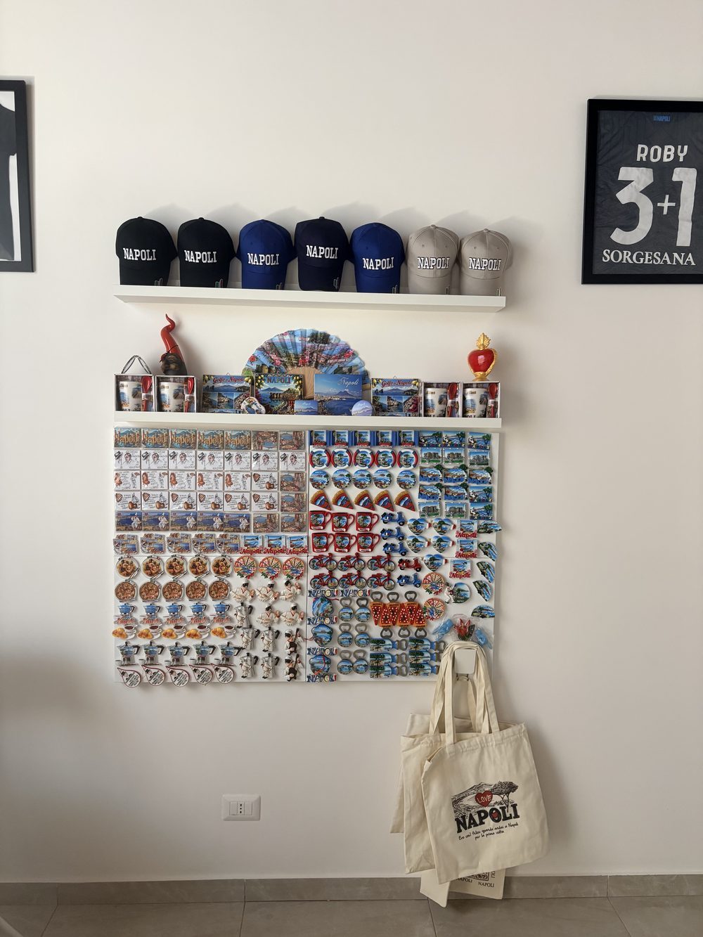 Angolo souvenir all'ingresso con cappellini e gadget di Napoli